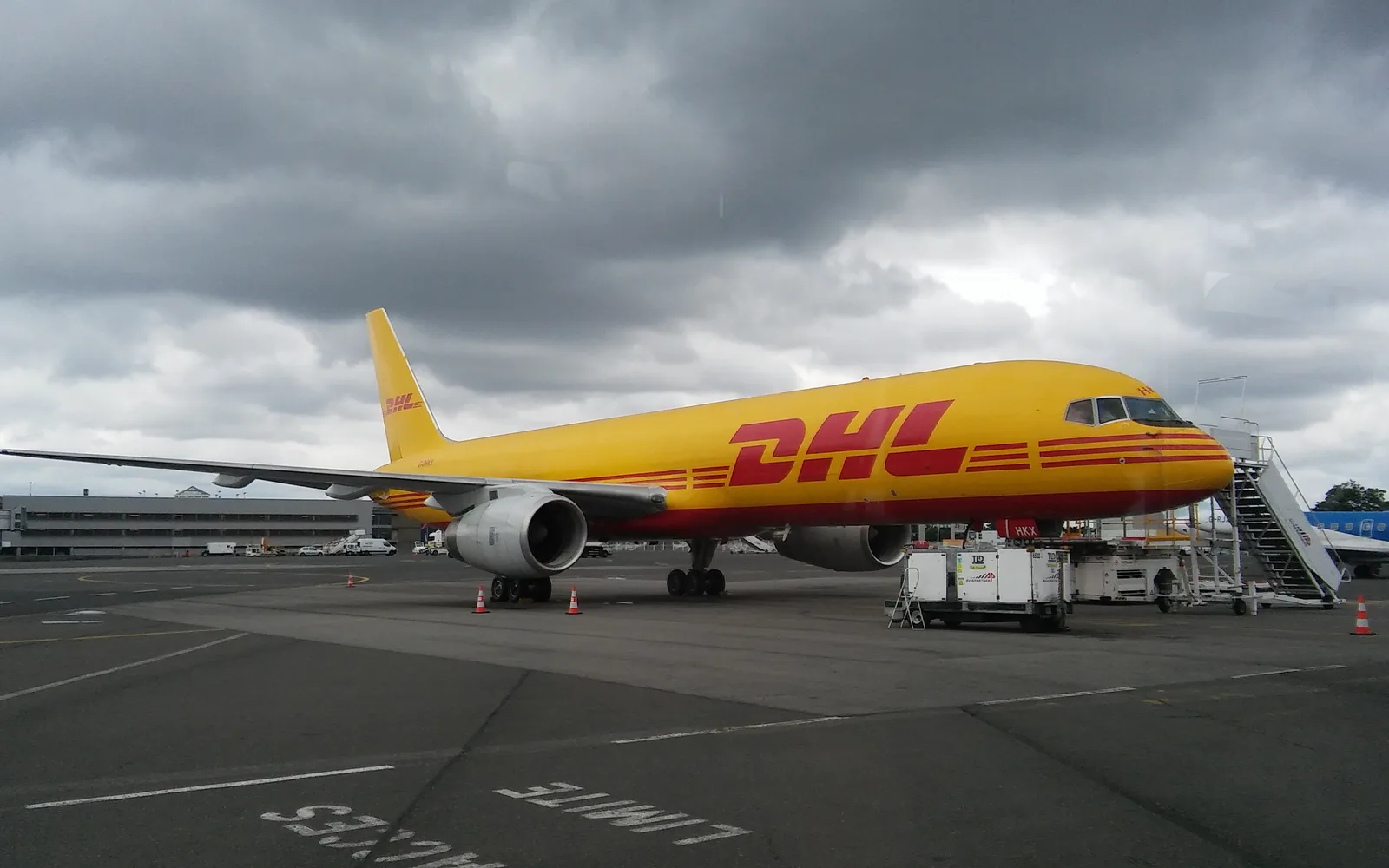 A DHL cargo aircraft Boeing 757-200 parked at an airport terminal